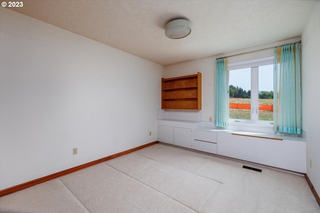 spare room featuring light carpet and a textured ceiling