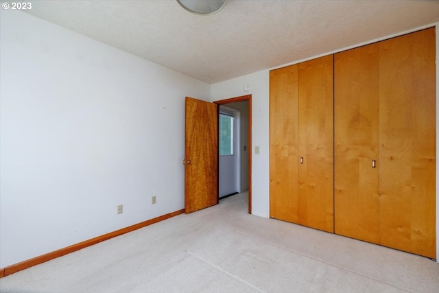 unfurnished bedroom with a textured ceiling, light carpet, and a closet