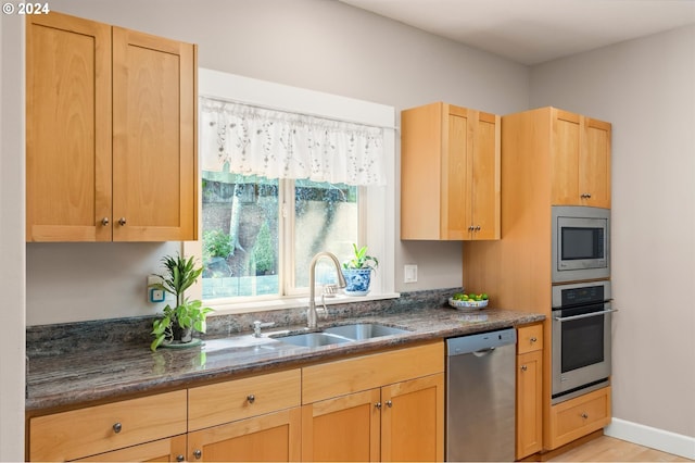 kitchen featuring appliances with stainless steel finishes, sink, and dark stone counters