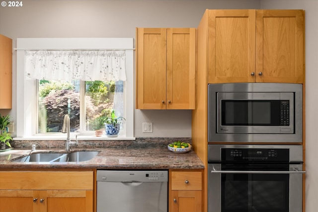 kitchen featuring stainless steel appliances, sink, and dark stone counters