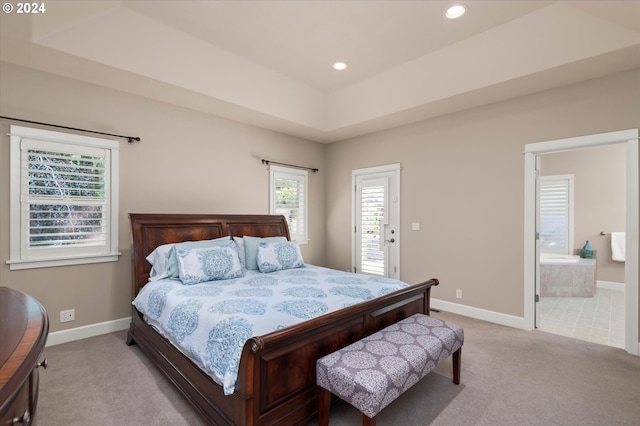 carpeted bedroom featuring connected bathroom and a tray ceiling