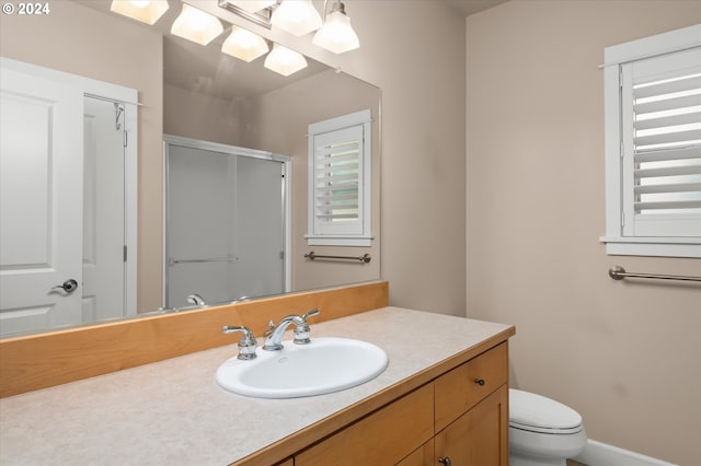 bathroom with vanity, a shower with shower door, and toilet