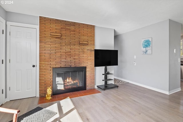 unfurnished living room featuring hardwood / wood-style floors and a brick fireplace