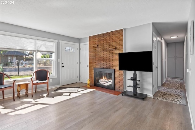 living room featuring a textured ceiling, hardwood / wood-style floors, and a brick fireplace