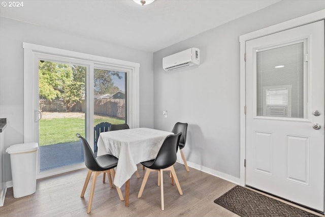 dining space with an AC wall unit and light hardwood / wood-style floors