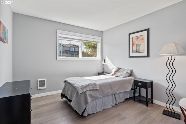 bedroom with hardwood / wood-style flooring and heating unit