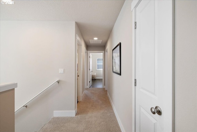 hallway featuring light carpet and a textured ceiling