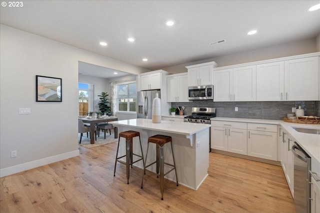 kitchen with light hardwood / wood-style flooring, appliances with stainless steel finishes, a center island, and white cabinets