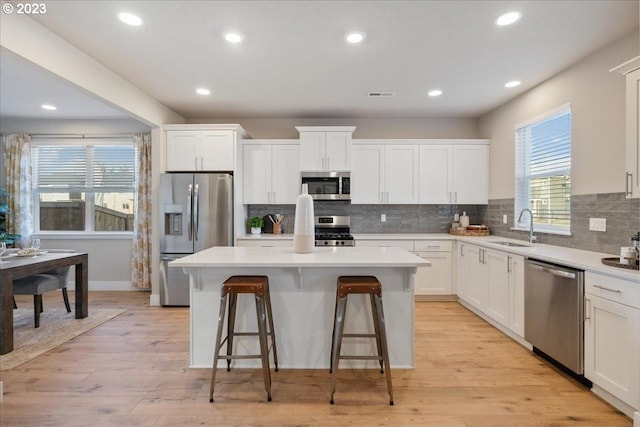 kitchen featuring a kitchen island, appliances with stainless steel finishes, light hardwood / wood-style flooring, and white cabinetry