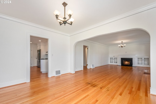 unfurnished living room with ornamental molding and hardwood / wood-style floors