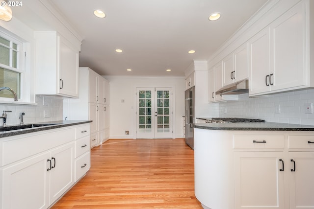 kitchen with light wood-type flooring, decorative backsplash, and white cabinets