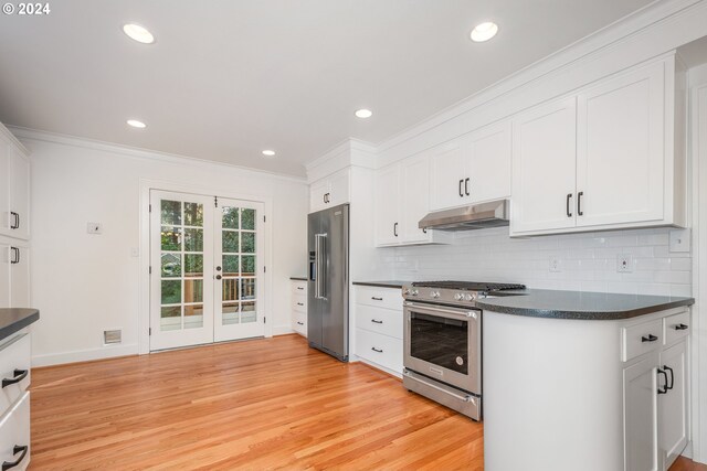 kitchen with stainless steel appliances, light hardwood / wood-style floors, decorative backsplash, and white cabinetry