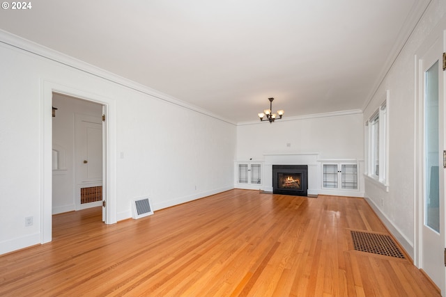 unfurnished living room with a notable chandelier, light wood-type flooring, and crown molding