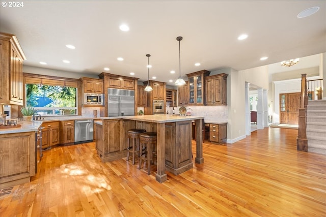 kitchen with built in appliances, a kitchen island, a kitchen breakfast bar, brown cabinetry, and glass insert cabinets