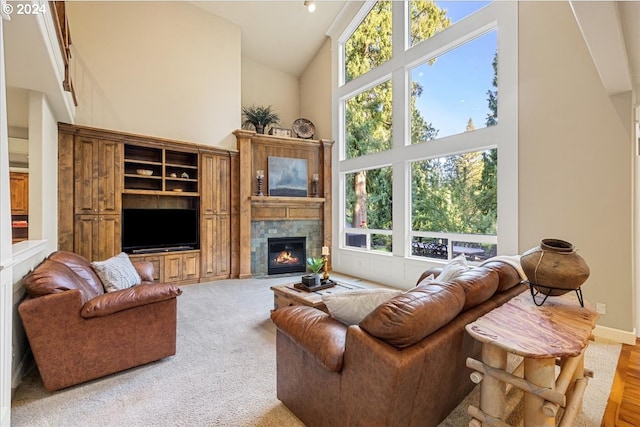 living area with high vaulted ceiling, a fireplace, and baseboards