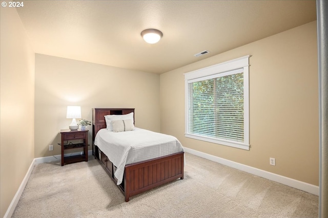 bedroom featuring visible vents, light carpet, and baseboards