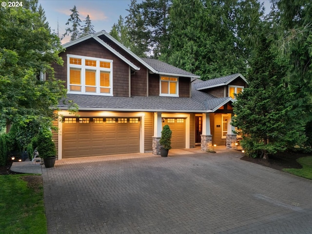 craftsman house featuring decorative driveway, an attached garage, and a shingled roof