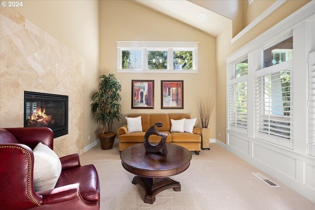 living area with baseboards, visible vents, carpet floors, a fireplace, and high vaulted ceiling