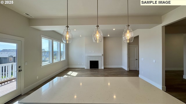 unfurnished living room featuring dark wood-style floors, a tiled fireplace, baseboards, visible vents, and recessed lighting