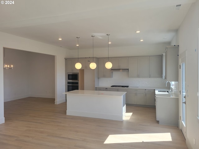 kitchen featuring backsplash, stainless steel appliances, light hardwood / wood-style flooring, gray cabinets, and a kitchen island