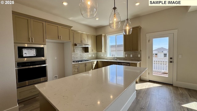 kitchen featuring under cabinet range hood, a sink, tasteful backsplash, appliances with stainless steel finishes, and dark wood-style flooring