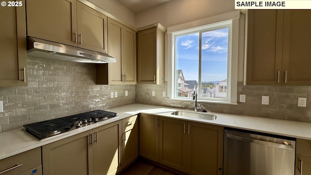 kitchen featuring a sink, backsplash, light countertops, under cabinet range hood, and appliances with stainless steel finishes