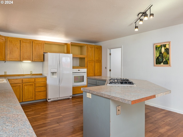 kitchen with white appliances, a textured ceiling, a center island, and dark hardwood / wood-style flooring