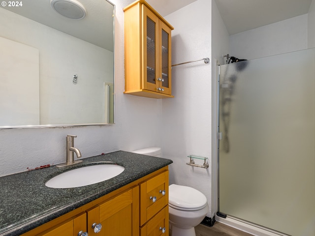 bathroom featuring wood-type flooring, vanity, toilet, and an enclosed shower