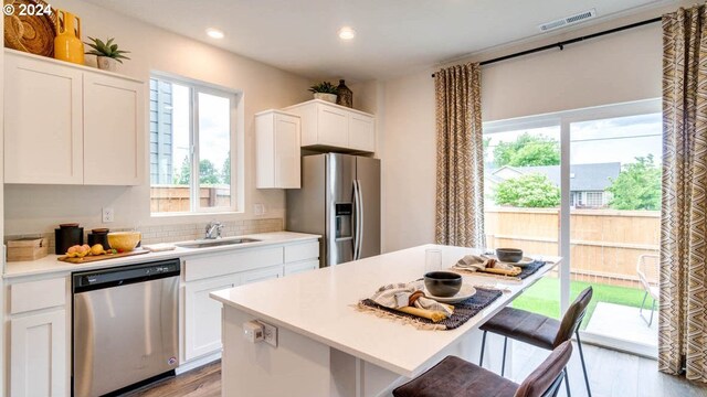 kitchen with a center island, sink, appliances with stainless steel finishes, a breakfast bar area, and white cabinets