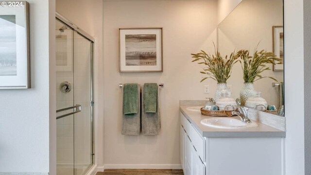 bathroom featuring a shower with shower door and vanity