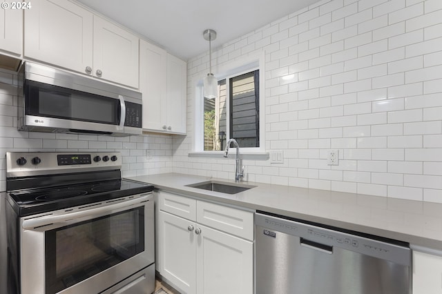 kitchen featuring white cabinetry, sink, hanging light fixtures, backsplash, and appliances with stainless steel finishes