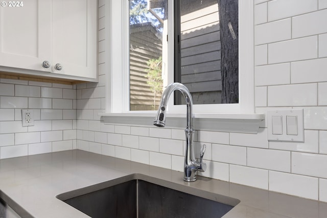 room details with decorative backsplash, sink, and white cabinets