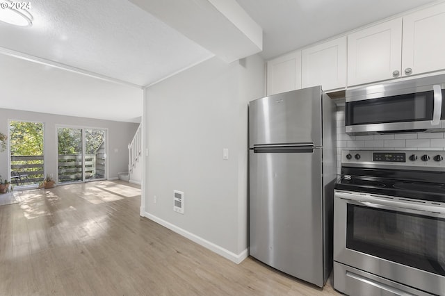 kitchen with white cabinetry, stainless steel appliances, light hardwood / wood-style flooring, backsplash, and a textured ceiling