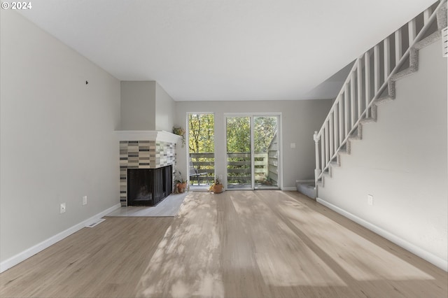 unfurnished living room featuring light hardwood / wood-style floors and a tile fireplace