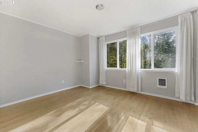 unfurnished room with heating unit and light hardwood / wood-style floors