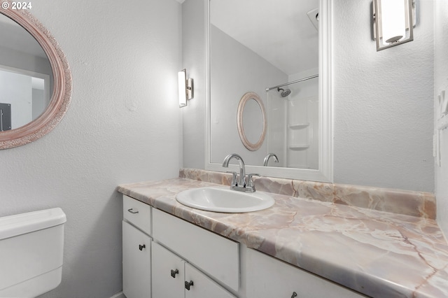 bathroom with a shower, vanity, and toilet