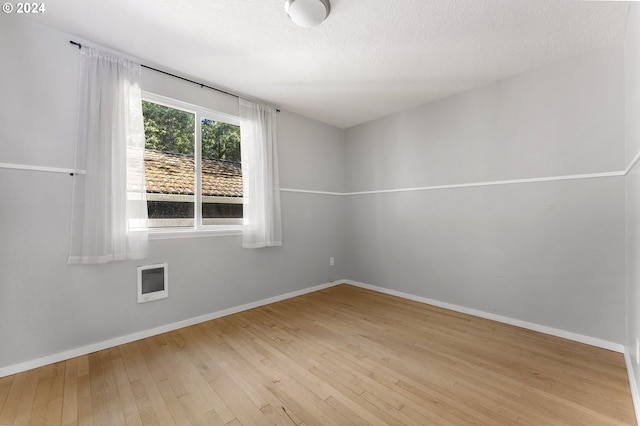 unfurnished room featuring light wood-type flooring and a textured ceiling