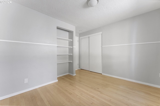 unfurnished bedroom featuring a textured ceiling, light hardwood / wood-style floors, and a closet