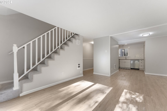 unfurnished living room featuring light wood-type flooring and sink