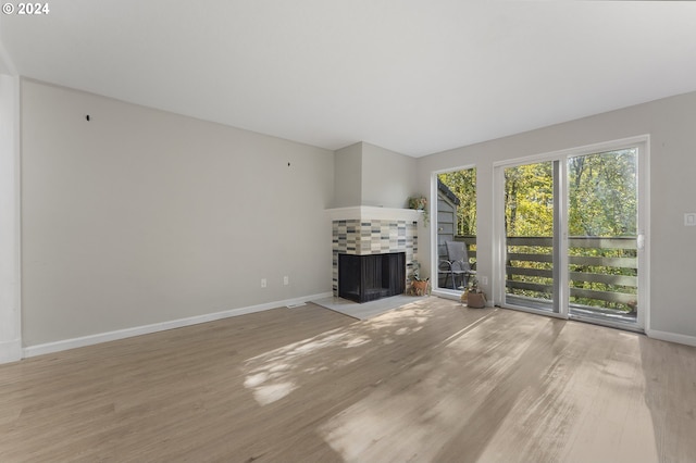 unfurnished living room with wood-type flooring and a tiled fireplace