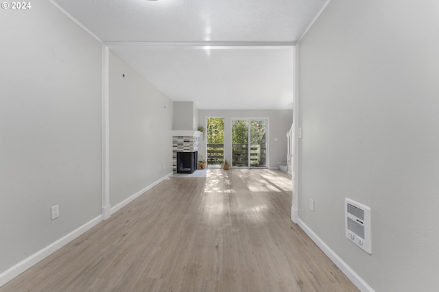 unfurnished living room with a fireplace, light hardwood / wood-style floors, a textured ceiling, and heating unit