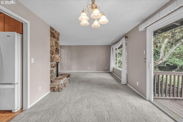 unfurnished living room featuring a textured ceiling, a chandelier, and carpet flooring