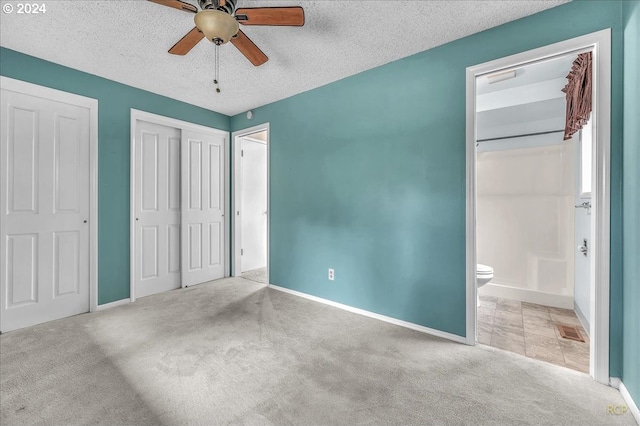 unfurnished bedroom with a textured ceiling, ceiling fan, light carpet, and multiple closets