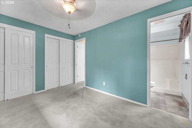 unfurnished bedroom with ceiling fan, carpet, multiple closets, and a textured ceiling