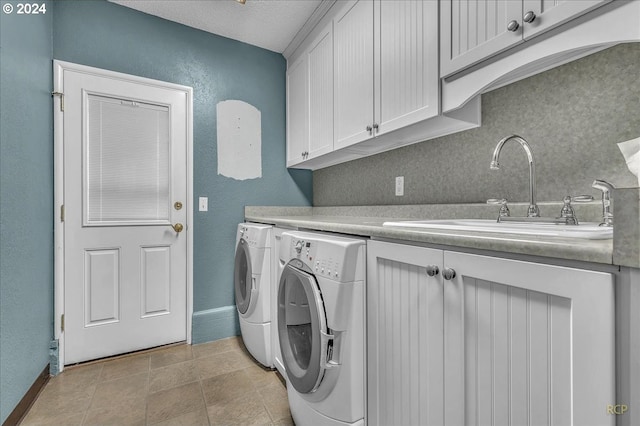 washroom featuring cabinets, a textured ceiling, light tile patterned floors, washing machine and dryer, and sink