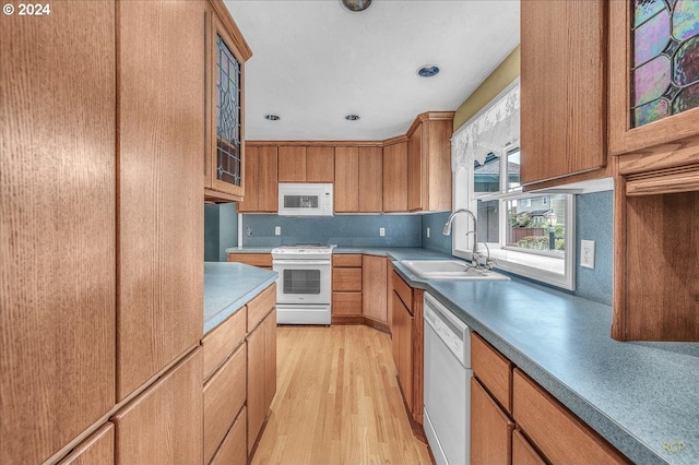 kitchen with light wood-type flooring, sink, and white appliances