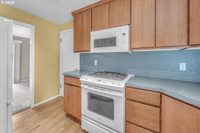 kitchen with white appliances, backsplash, and light hardwood / wood-style floors