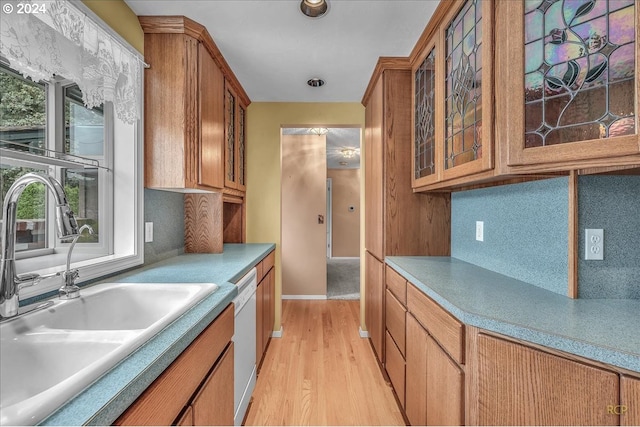 kitchen with light wood-type flooring, white dishwasher, decorative backsplash, and sink