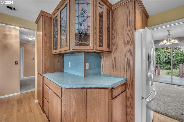 kitchen featuring light wood-type flooring, a chandelier, decorative backsplash, and white fridge with ice dispenser