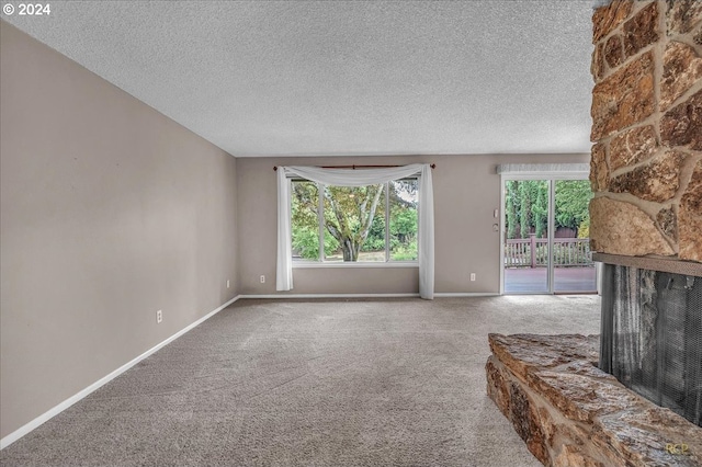 unfurnished living room with a fireplace, a textured ceiling, and carpet flooring